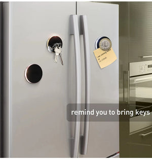 Stainless steel refrigerator with key holder and magnet on a kitchen wall.