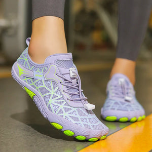 Purple athletic shoes with green accents worn by a person on a blurred background