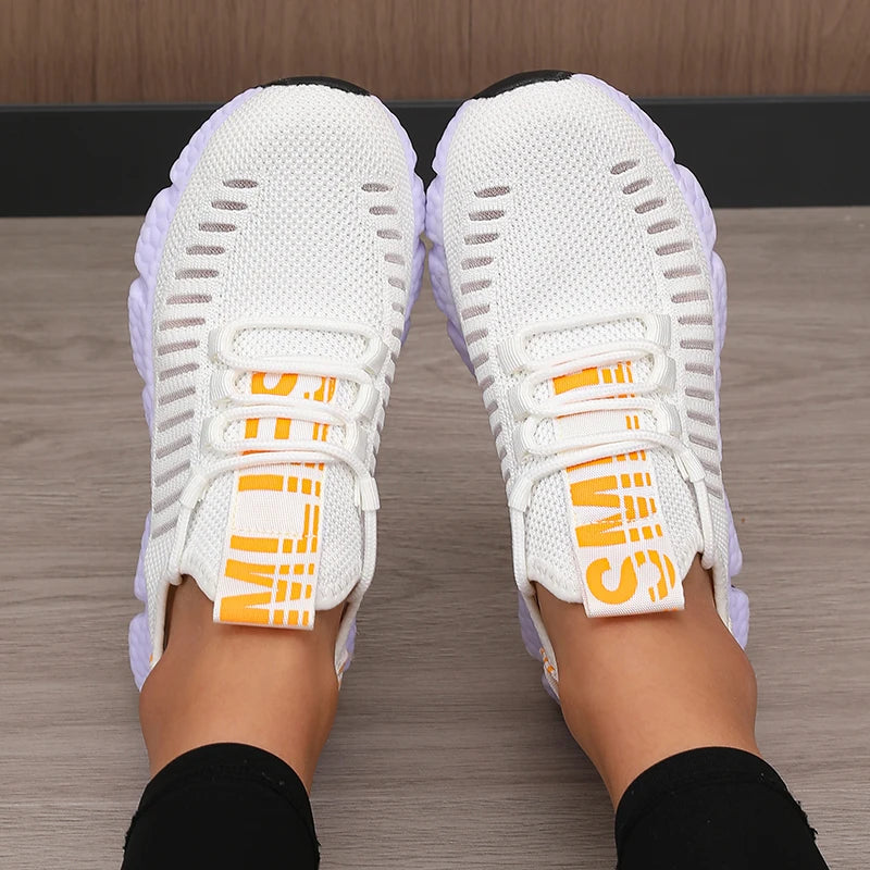 White sneakers with orange accents worn on a wooden floor