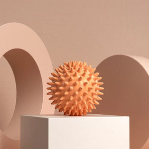 Orange textured ball on a white platform with a beige background
