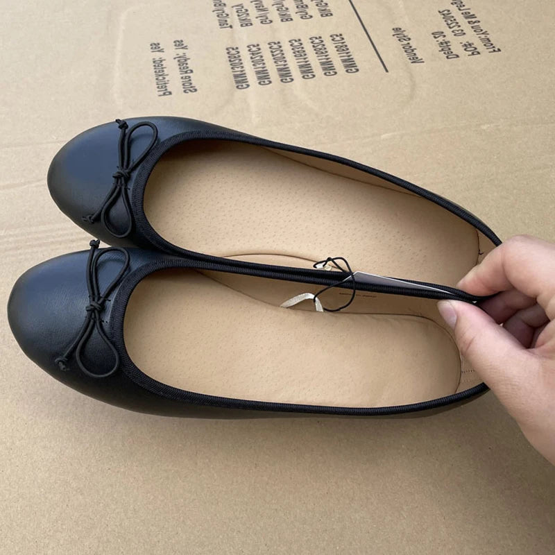 Black ballet flats being held above a cardboard box