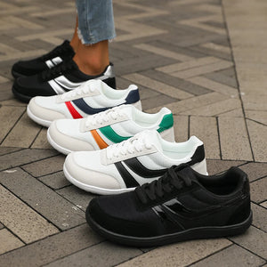 Four pairs of sneakers in black, white, and multicolor on a patterned pavement.