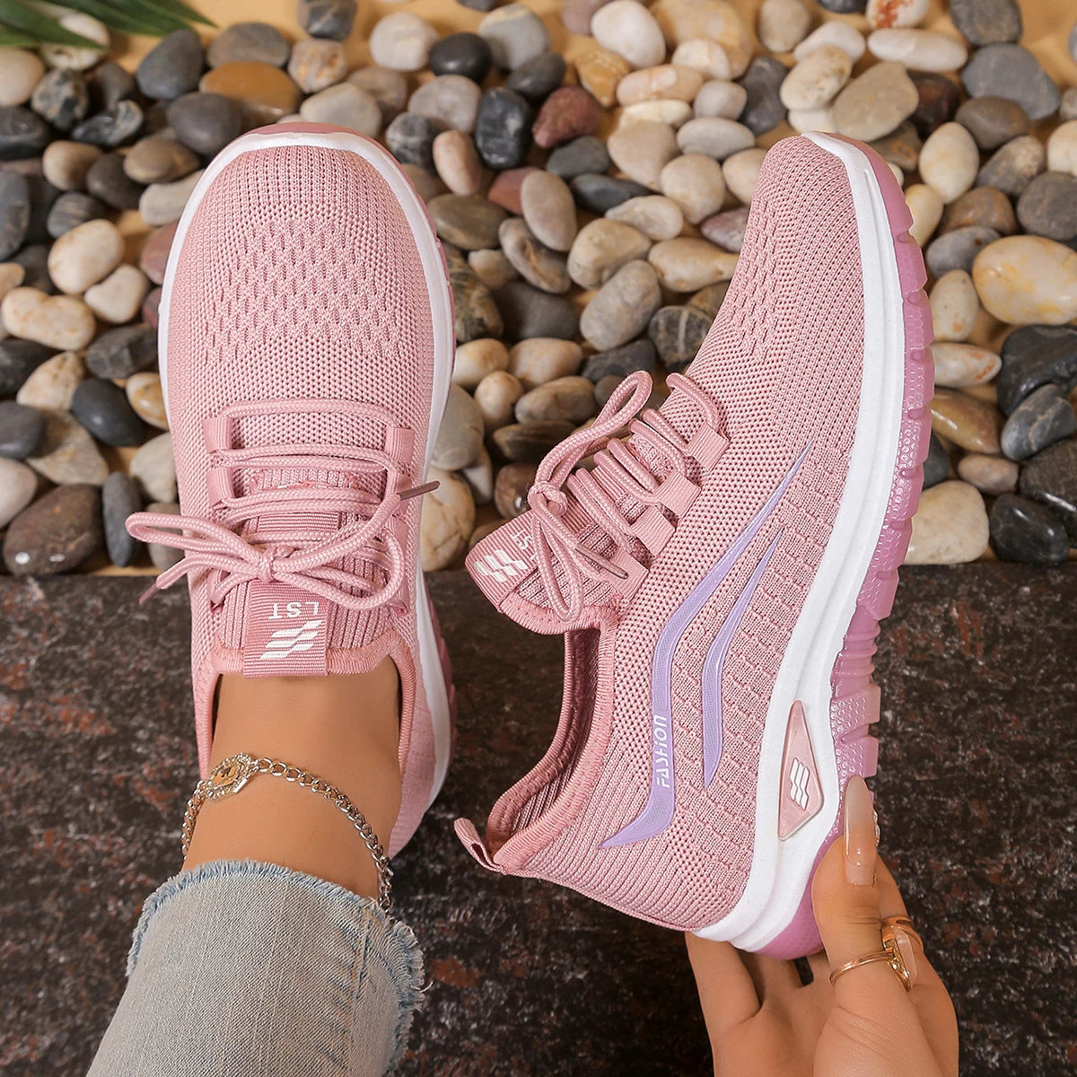 Pink athletic shoes with white soles on a pebble surface
