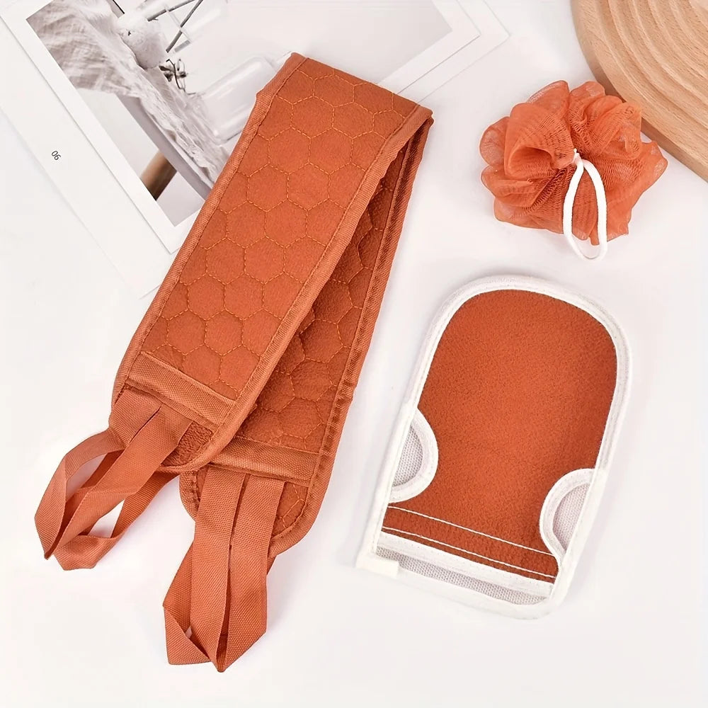 Set of orange bath items including a loofah, scrubber, and mitt on a white surface.