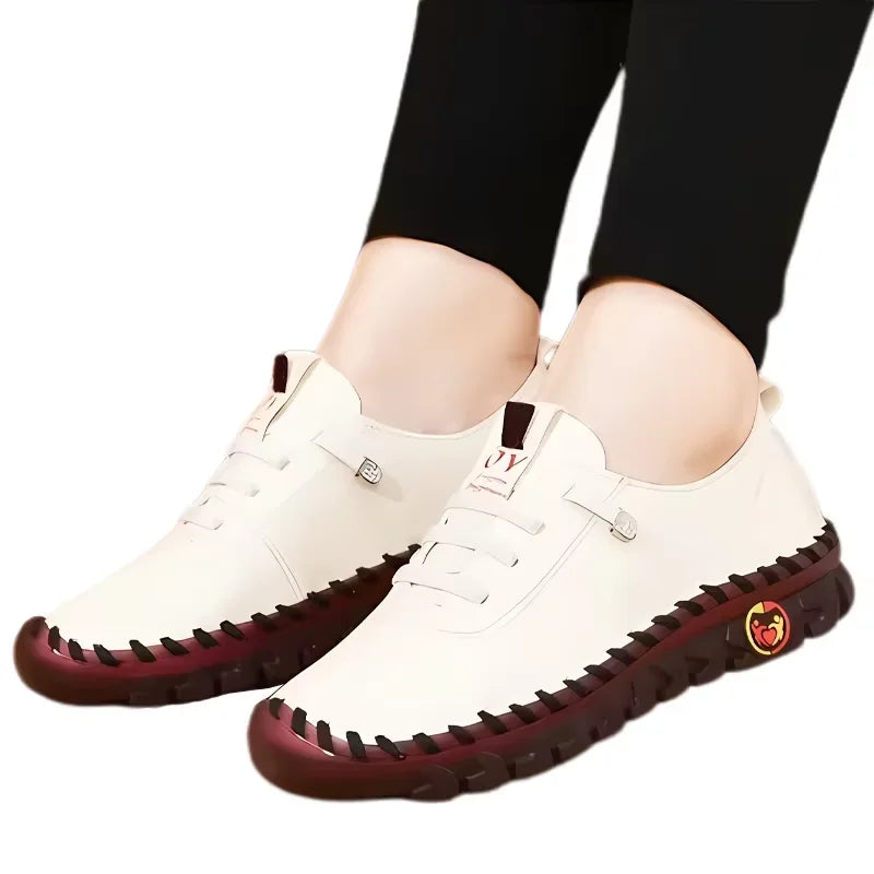 White sneakers with red soles worn by a person on a white background
