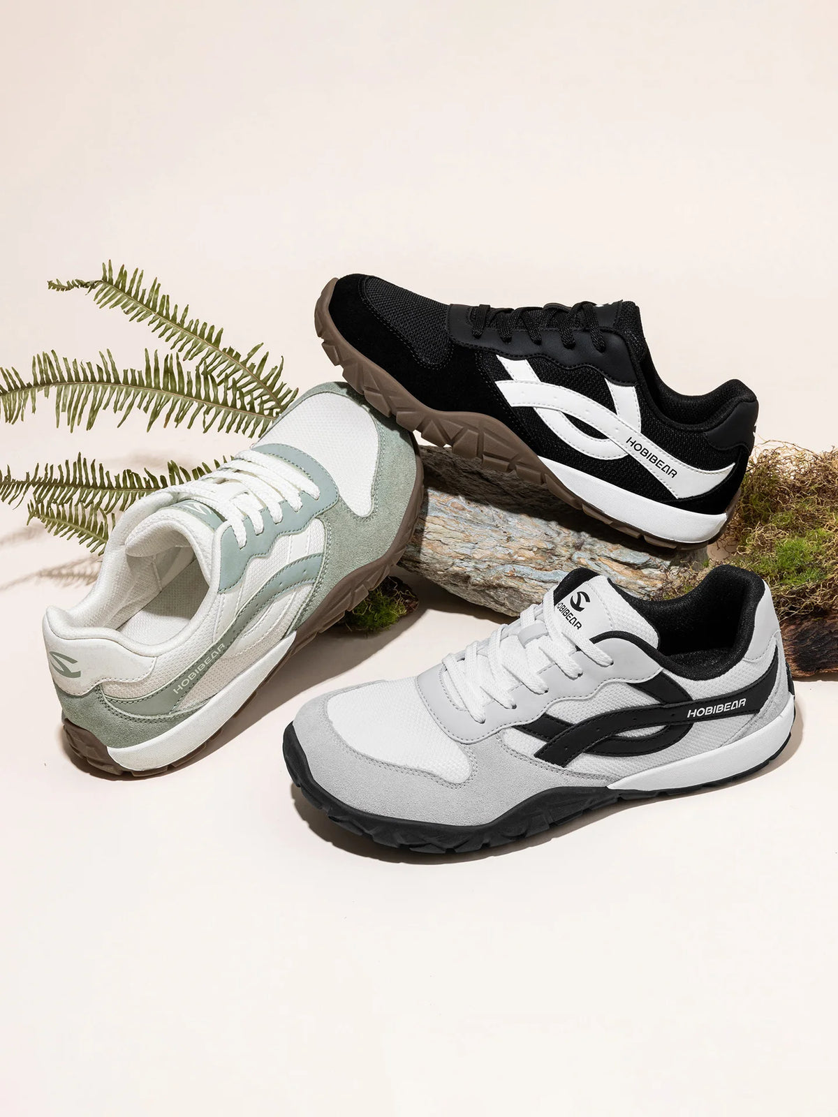 Three pairs of shoes in different colors on a light background with natural elements.