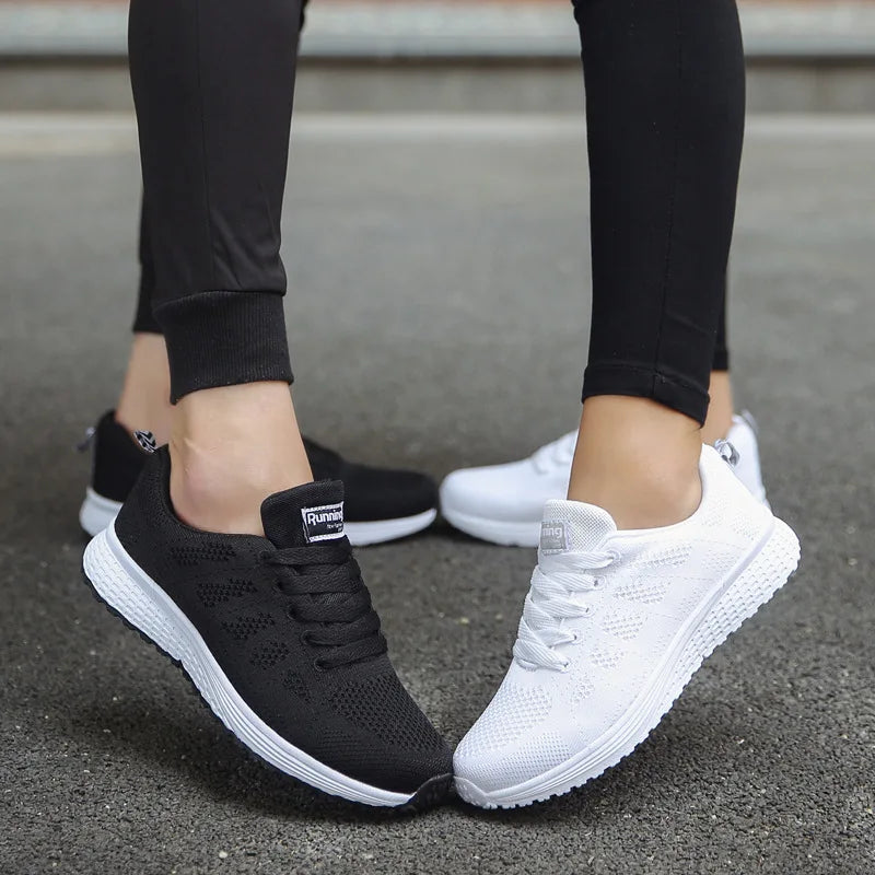 Black and white running shoes worn on a gray pavement background