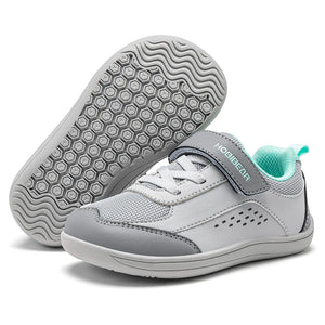 A pair of children's casual sneakers in light gray and white, with one shoe showing the textured gray outsole and the other showing the side profile with a hook-and-loop strap and mint green lining.