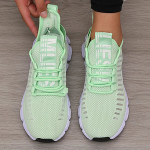Light green sneakers with white soles on a wooden floor