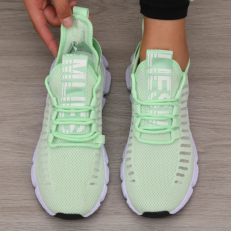 Light green sneakers with white soles on a wooden floor
