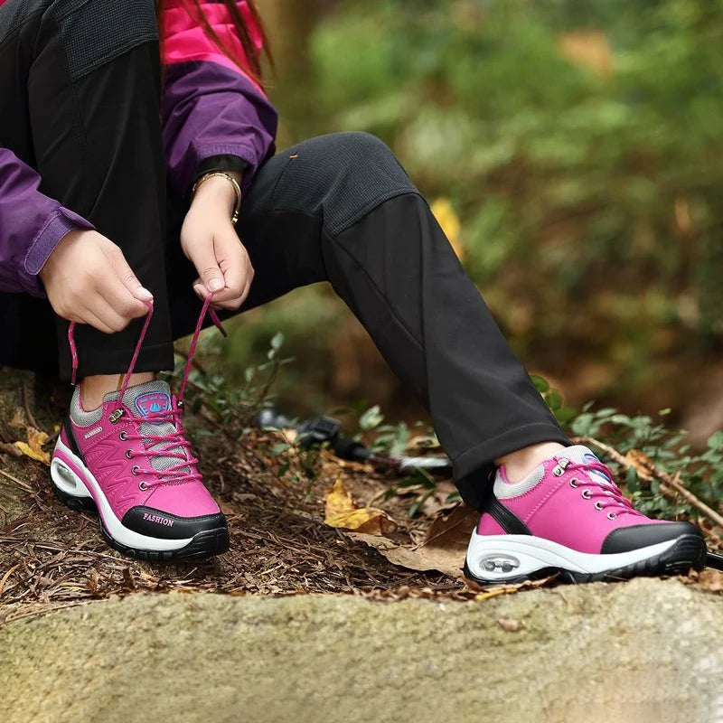 Person tying pink hiking shoes in a forest setting