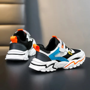 Pair of black, white, and blue sneakers with orange accents on a dark surface.