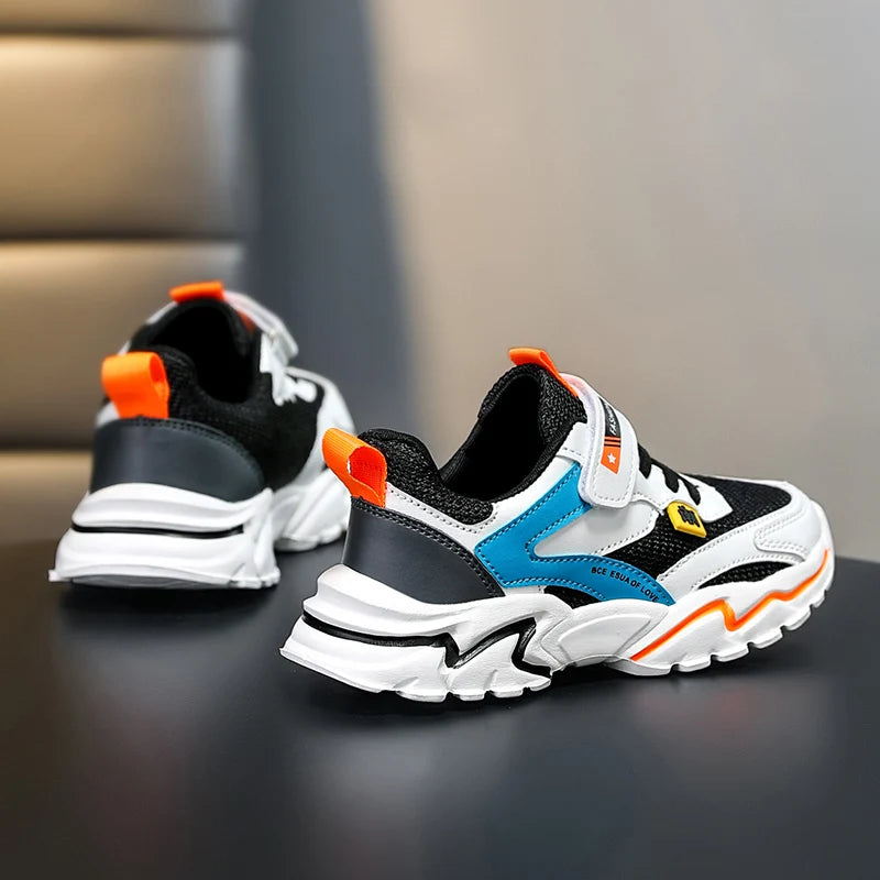 Pair of black, white, and blue sneakers with orange accents on a dark surface.
