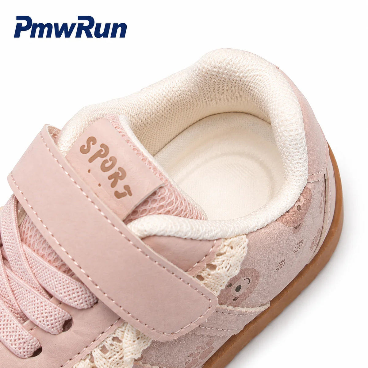 A close-up of a children's sneaker in light pink suede and mesh with a hook-and-loop strap, lace-up closure, lace, cream lining, and a brown rubber sole