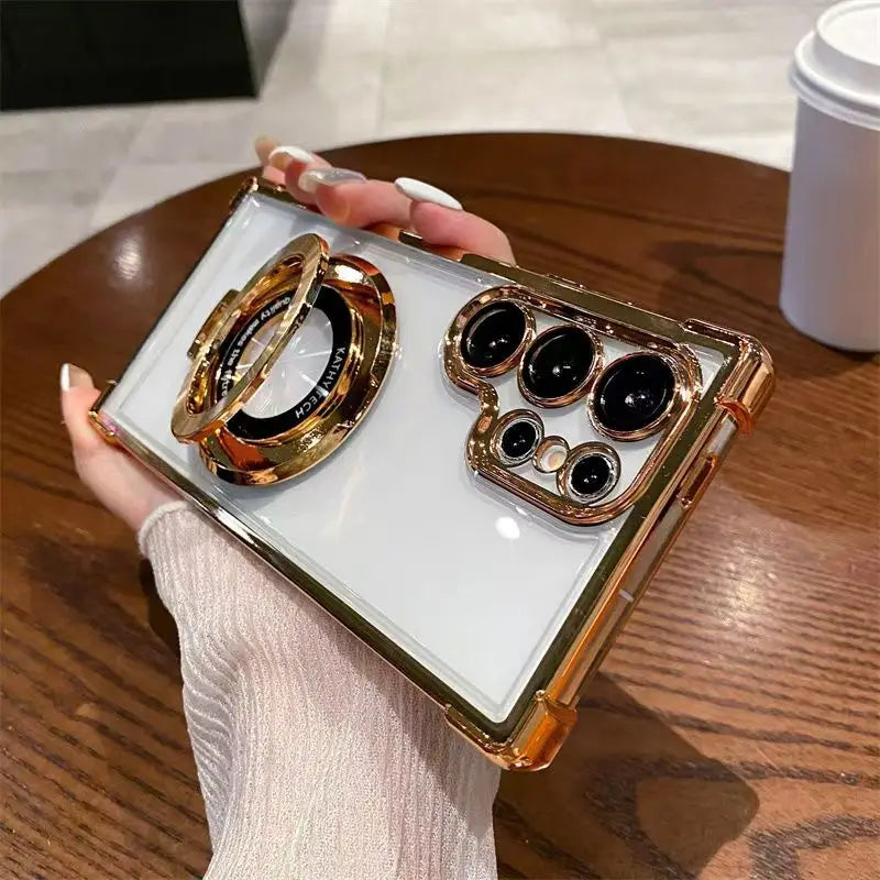 Luxury Clear Samsung Galaxy case with electroplated frame and magnetic ring stand with gold accents held by a person.