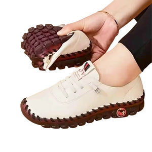 White shoe with brown sole held by a hand, Women's lace-up split leather casual flats with round toes and rubber outsoles