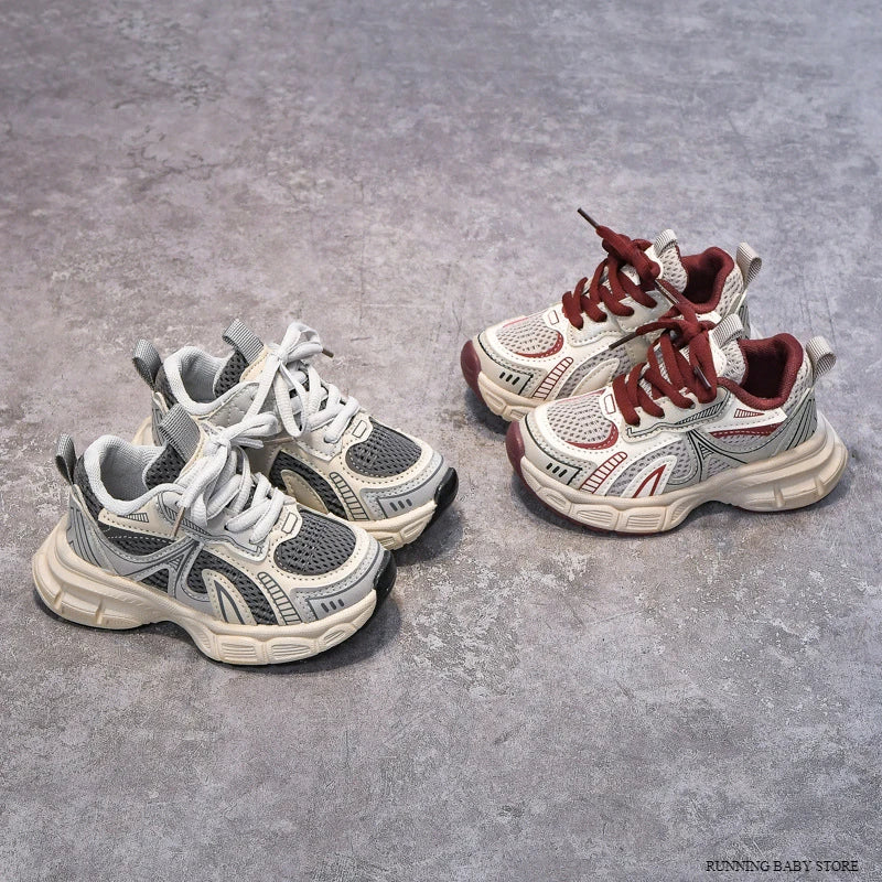 Two pairs of children's sneakers on a gray concrete surface.