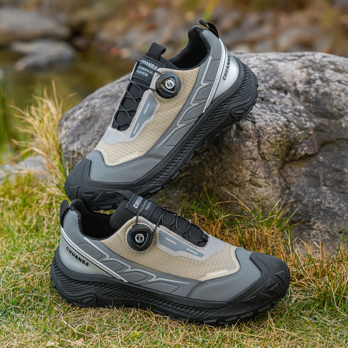 Pair of hiking shoes on a rock with grass and water in the background