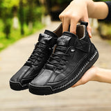 Black leather shoes held by a person with a blurred green outdoor background