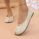 White flat shoes worn on a beige surface with a blurred colorful background