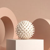 White textured sphere on a white pedestal against a beige background