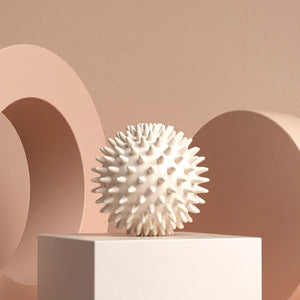 White textured sphere on a white pedestal against a beige background