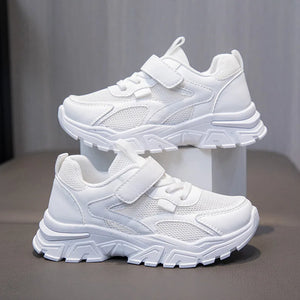 White children's sneakers with velcro straps on a gray background