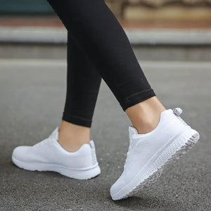 White sneakers worn with black leggings on a blurred background