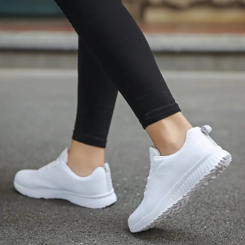 White sneakers worn with black leggings on a blurred background