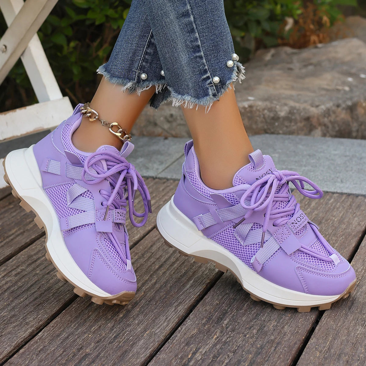 Purple sneakers worn on a wooden floor with a blurred outdoor background