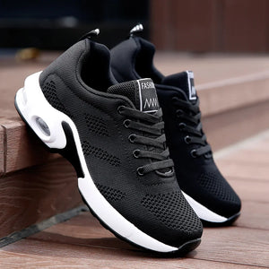Black athletic shoes with white soles on a wooden surface