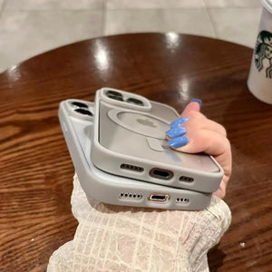 Person holding two phone cases on a wooden table in the background