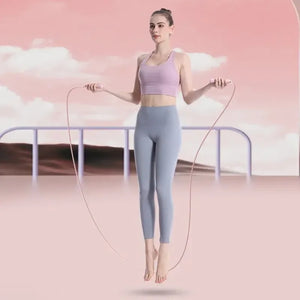 Woman skipping Smart jump rope against a pink background with clouds