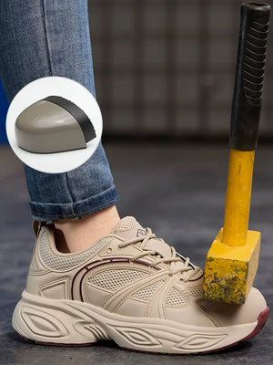 A beige safety work shoe with a thick textured sole, shown on a person's foot with a yellow-and-black mallet resting against the toe area. A circular inset highlights the protective toe cap.
