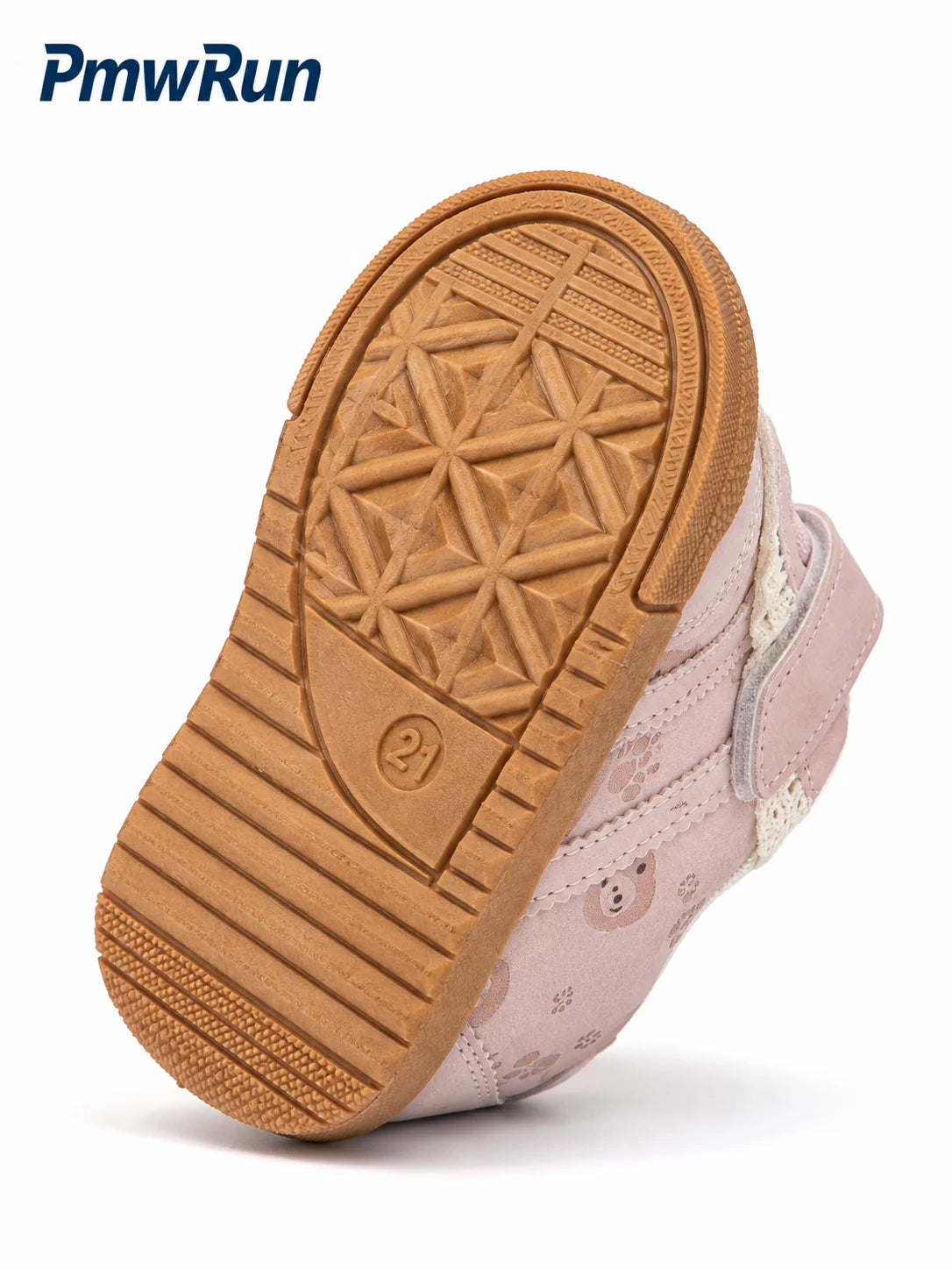 A close-up of a child's sneaker showing the tan textured rubber outsole and light pink upper