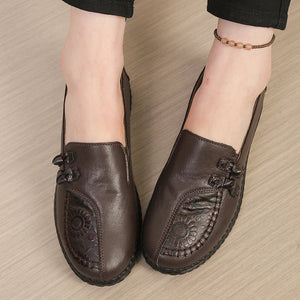 Brown leather shoes with floral patterns on a beige surface