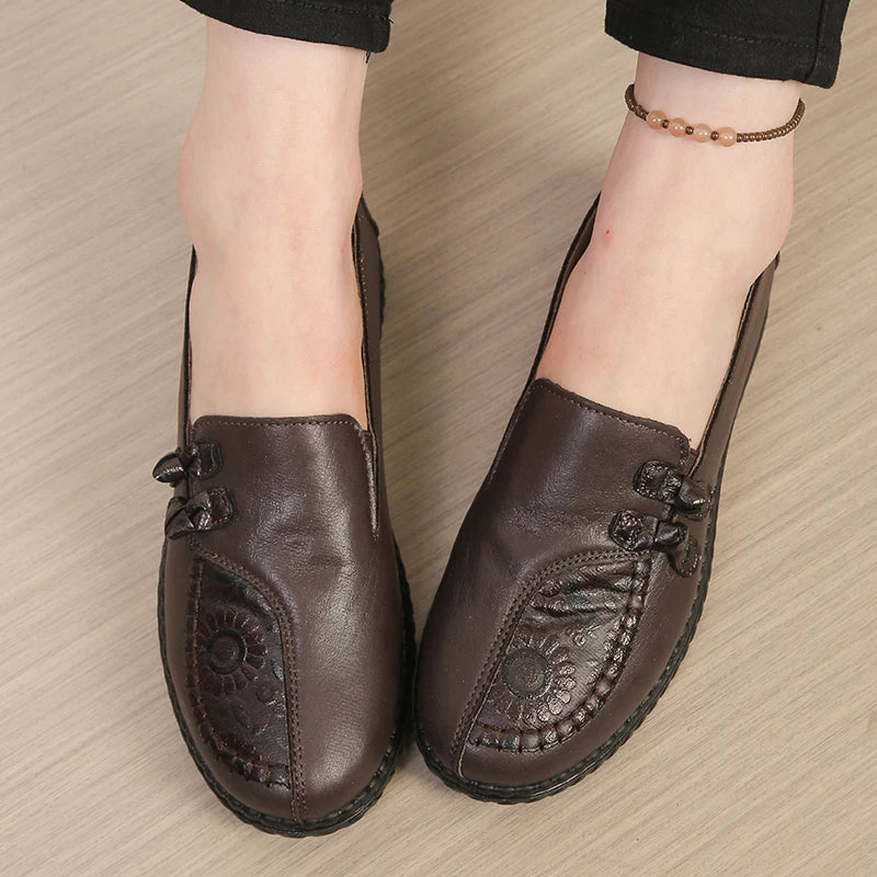 Brown leather shoes with floral patterns on a beige surface