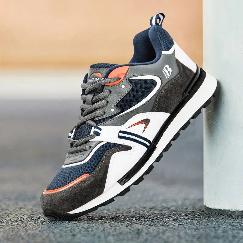 Navy, gray, and white sneaker with orange accents on a blurred background