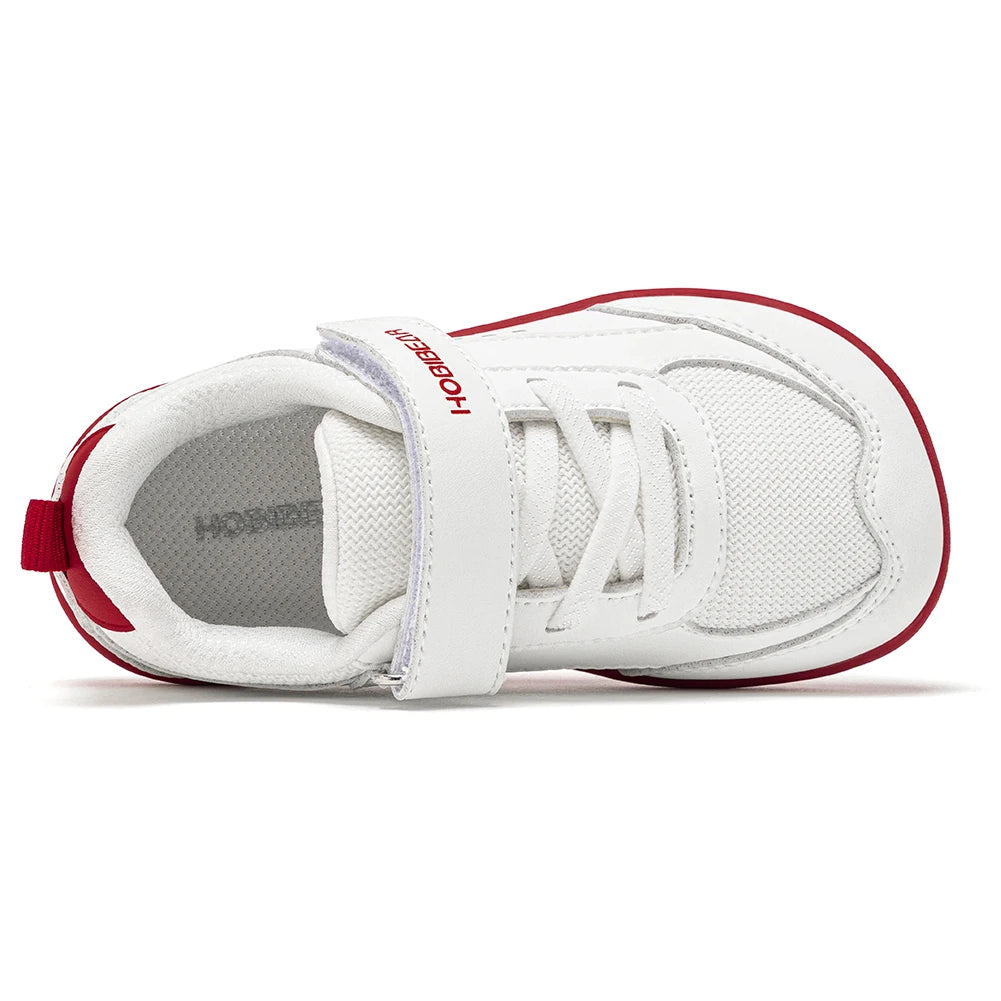 A white baby sneaker with red accents, featuring a hook-and-loop strap with 'hossey' printed in red on the side, a red heel pull tab, and a red outsole edge, shown from a side profile view on a white background.