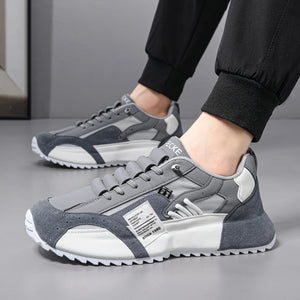 Gray and white sneakers worn with black pants on a neutral background