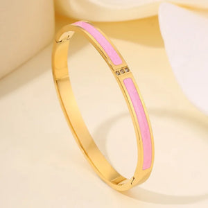 Gold bracelet with a pink enamel inset on a soft beige background