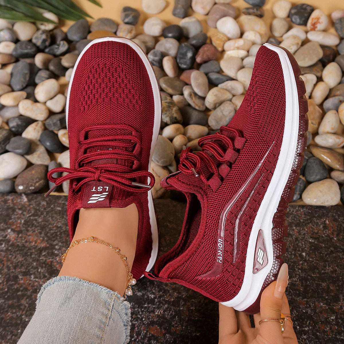 Red running shoes with white soles on a pebble background