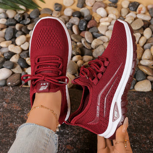 Red running shoes with white soles on a pebble background