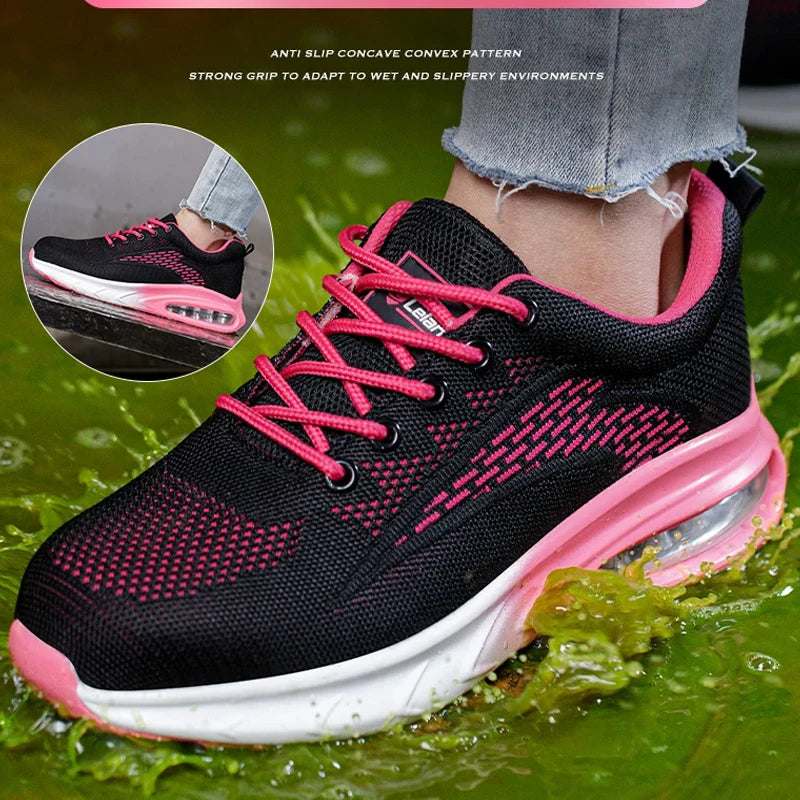 Black and pink Women's Safety Work Shoes with a breathable mesh upper, pink laces, and a white and pink cushioned sole, shown being worn with cuffed jeans over green water. A circular inset shows the shoe on a wet surface, with marketing text at the top.