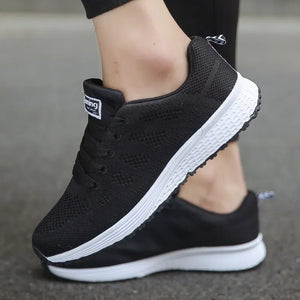 Black running shoes with white soles worn by a person on a blurred background