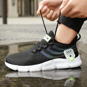 Person tying a black athletic shoe with white sole on a wet pavement.