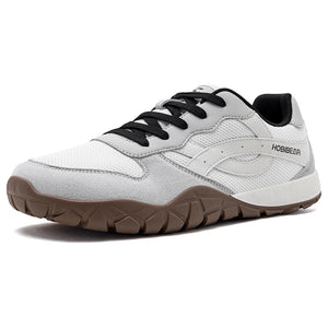 A white and light gray athletic sneaker with black laces, a black interior lining, and a brown textured sole, shown from a three-quarters angle on a white background.