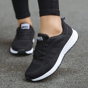 Black running shoes with white soles worn by a person on a gray surface