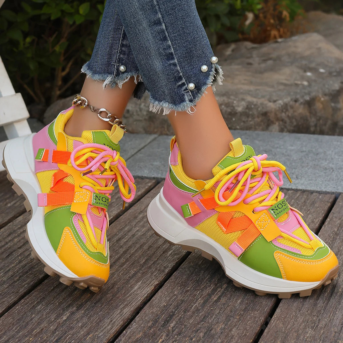 Colorful sneakers with a patterned sole worn on a wooden surface.