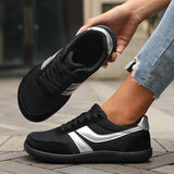 Person wearing black and silver athletic shoes on a pavement background